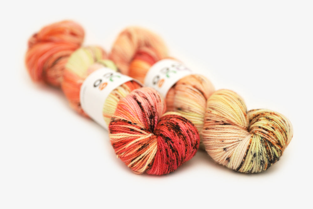 speckled hand dyed bright orange coral pink merino sock yarn