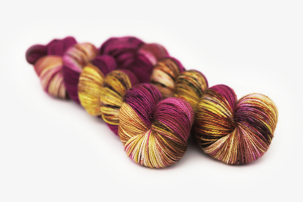 speckled hand dyed magenta gold olive merino sock yarn