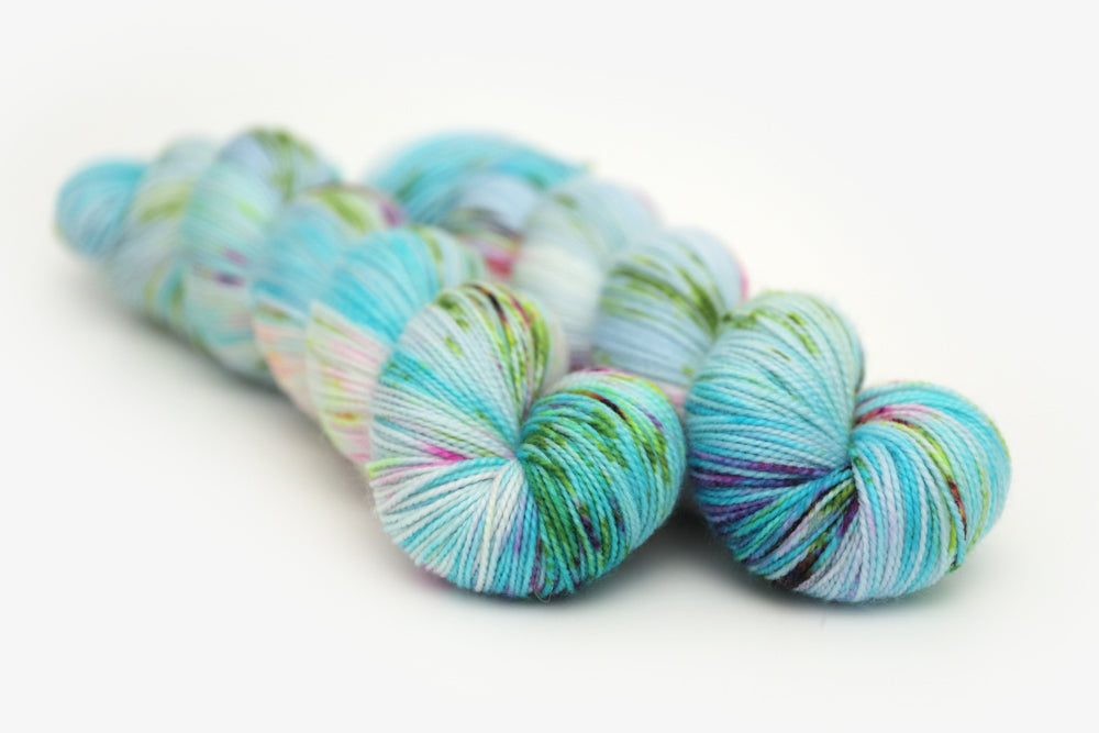 speckled hand dyed bright aqua green purple merino sock yarn