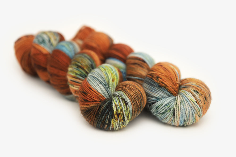 speckled hand dyed burnt orange teal green merino sock yarn
